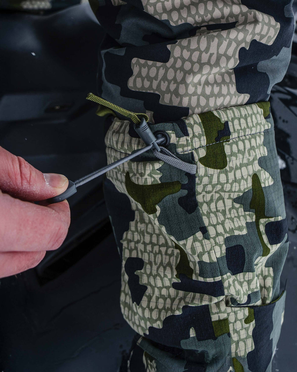 Hunter pulling on cordlock adjusting cuff on Super Down Arktuk Mitt in Verde Camouflage