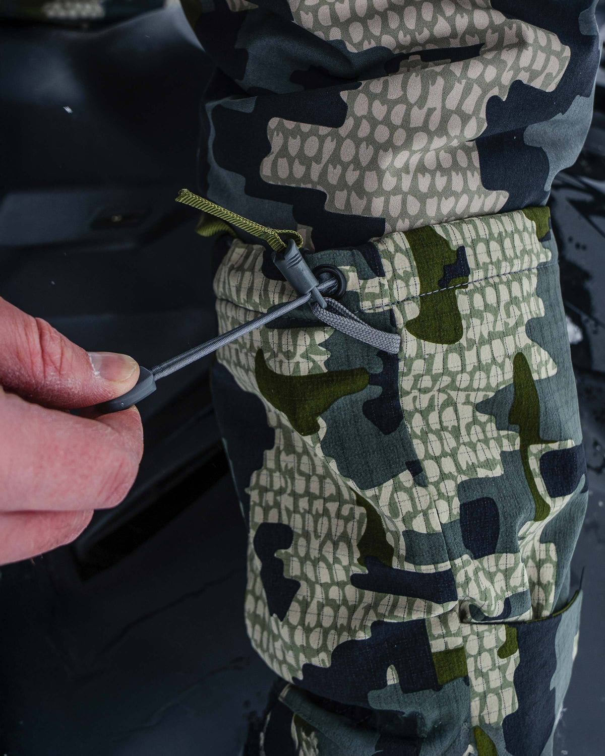 Hunter pulling on cordlock adjusting cuff on Super Down Arktuk Mitt in Verde Camouflage