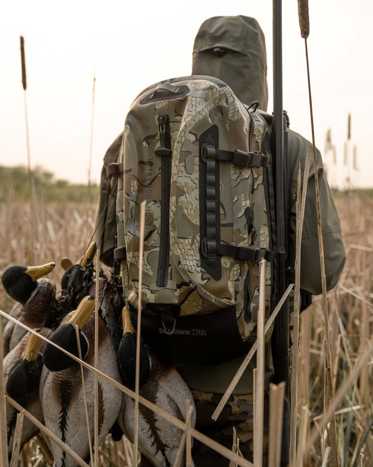 Delta Storm 2200 Submersible Backpack being worn by a hunter who is carrying a group of decoys facing away from the camera in Valo Camouflage