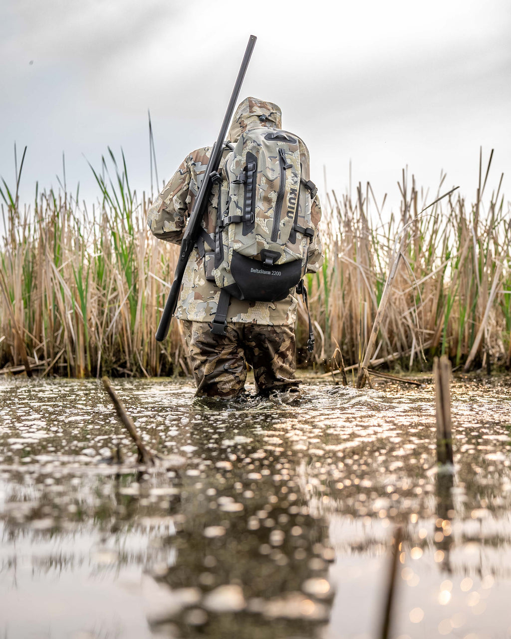 Delta Storm 2200 Submersible Backpack Being worn by a Man in the water walking away from the camera in Valo Camouflage