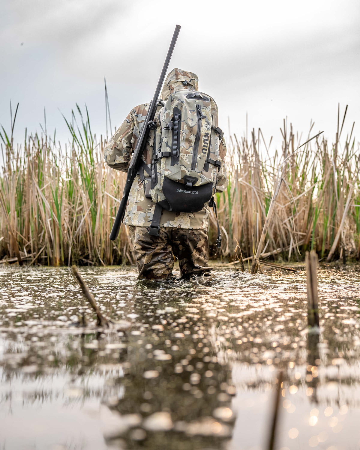 Delta Storm 2200 Submersible Backpack Being worn by a Man in the water walking away from the camera in Valo Camouflage