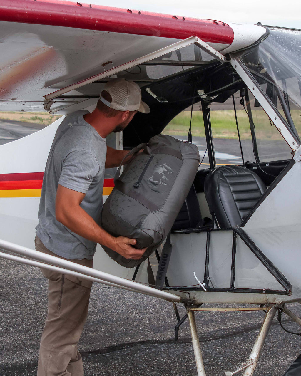 Man unloading Runway CORDURA® Duffel in Asphalt Grey from a  Super Cub plane