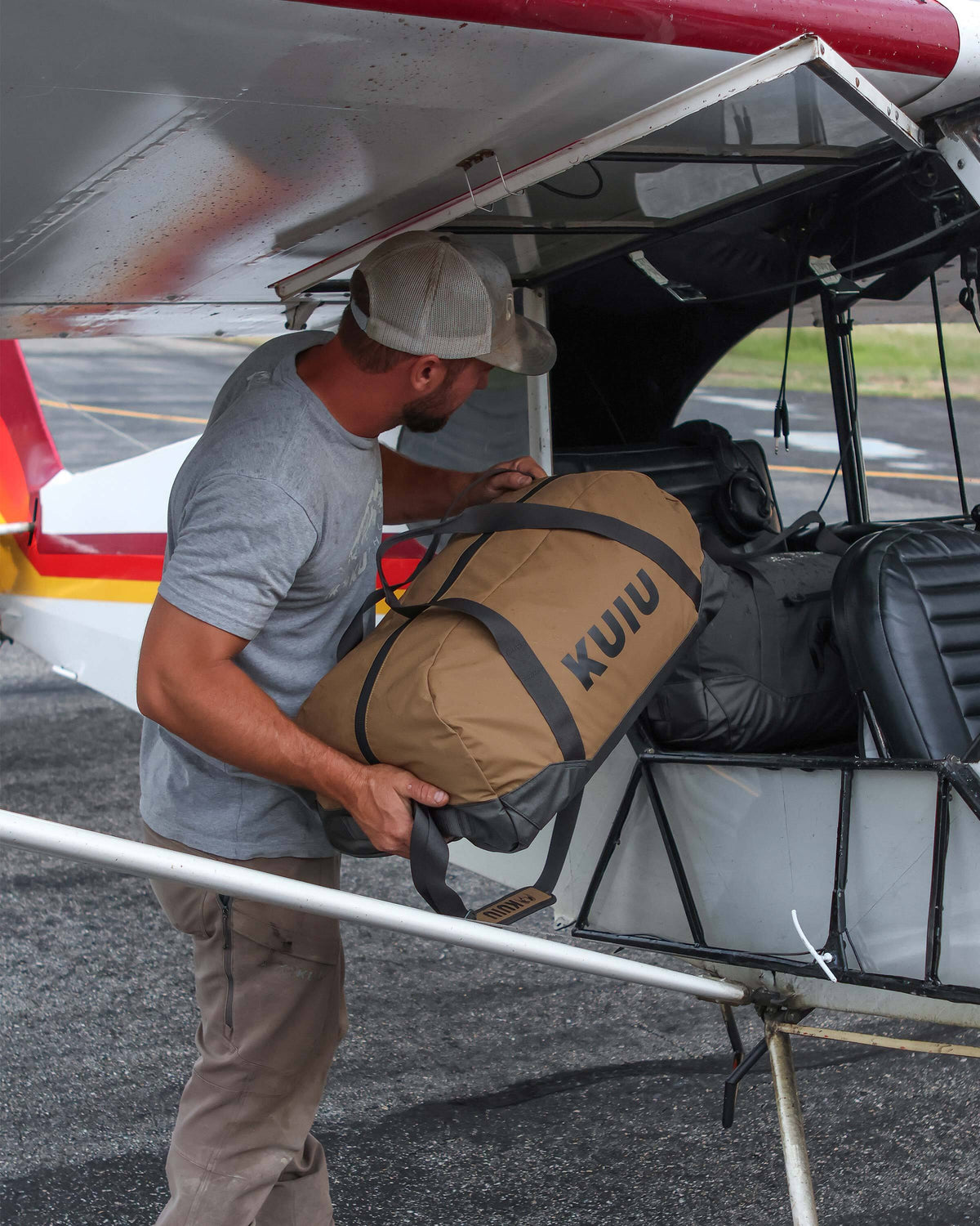 Man loading a Runway CORDURA® 3000 Duffel in Coyote Brown into a Super Cub plane