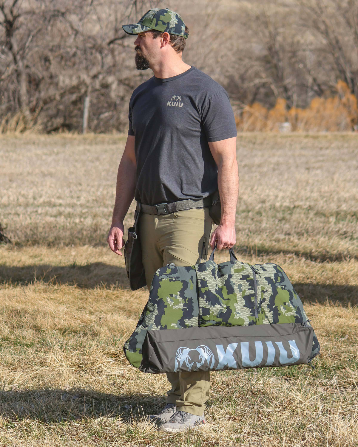 Hunter Standing in Open Field with Bow Travel Cover in Verde Camouflage Highlighting Durable Carry Handle
