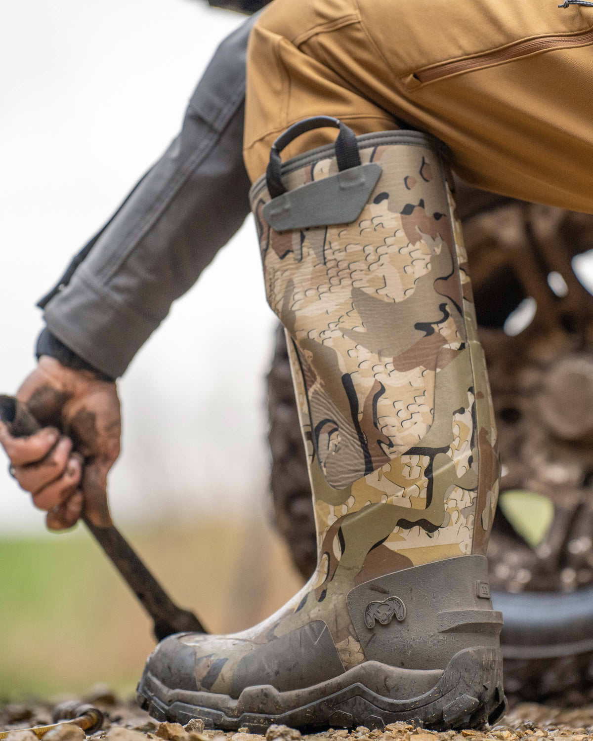 Close-up side view of KUIU Mud Boot in Valo Camouflage on a hunter kneeled down in an outdoor setting