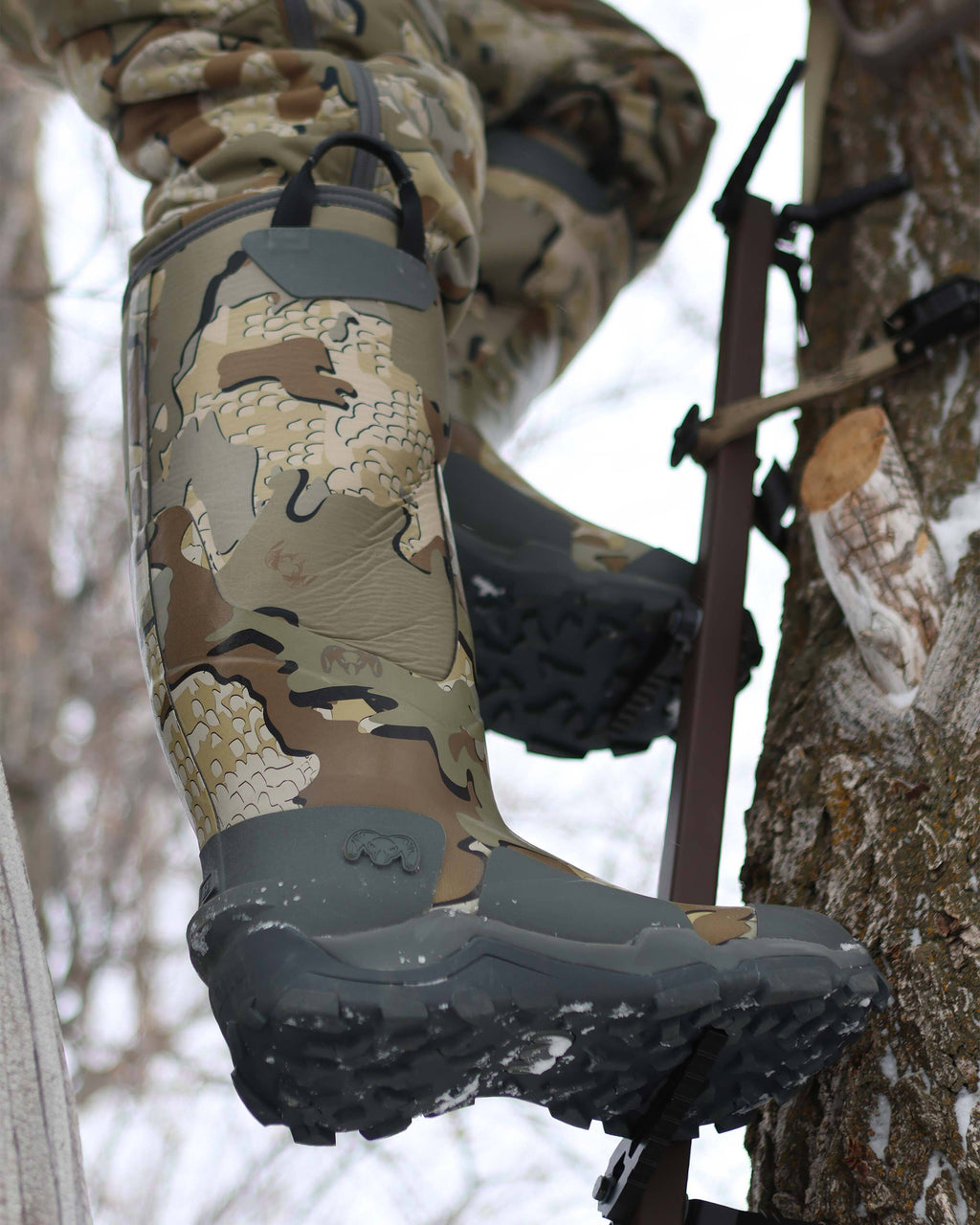 Hunter using a climbing stick on a tree, wearing KUIU Mud Boot in Valo Camouflage