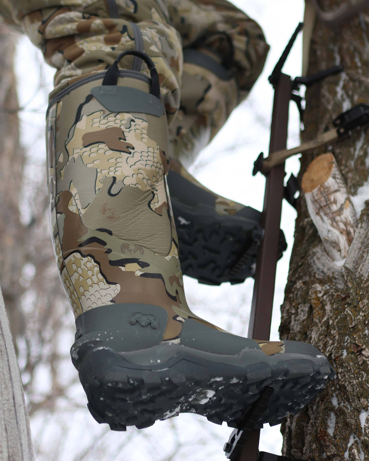 Hunter using a climbing stick on a tree, wearing KUIU Mud Boot in Valo Camouflage