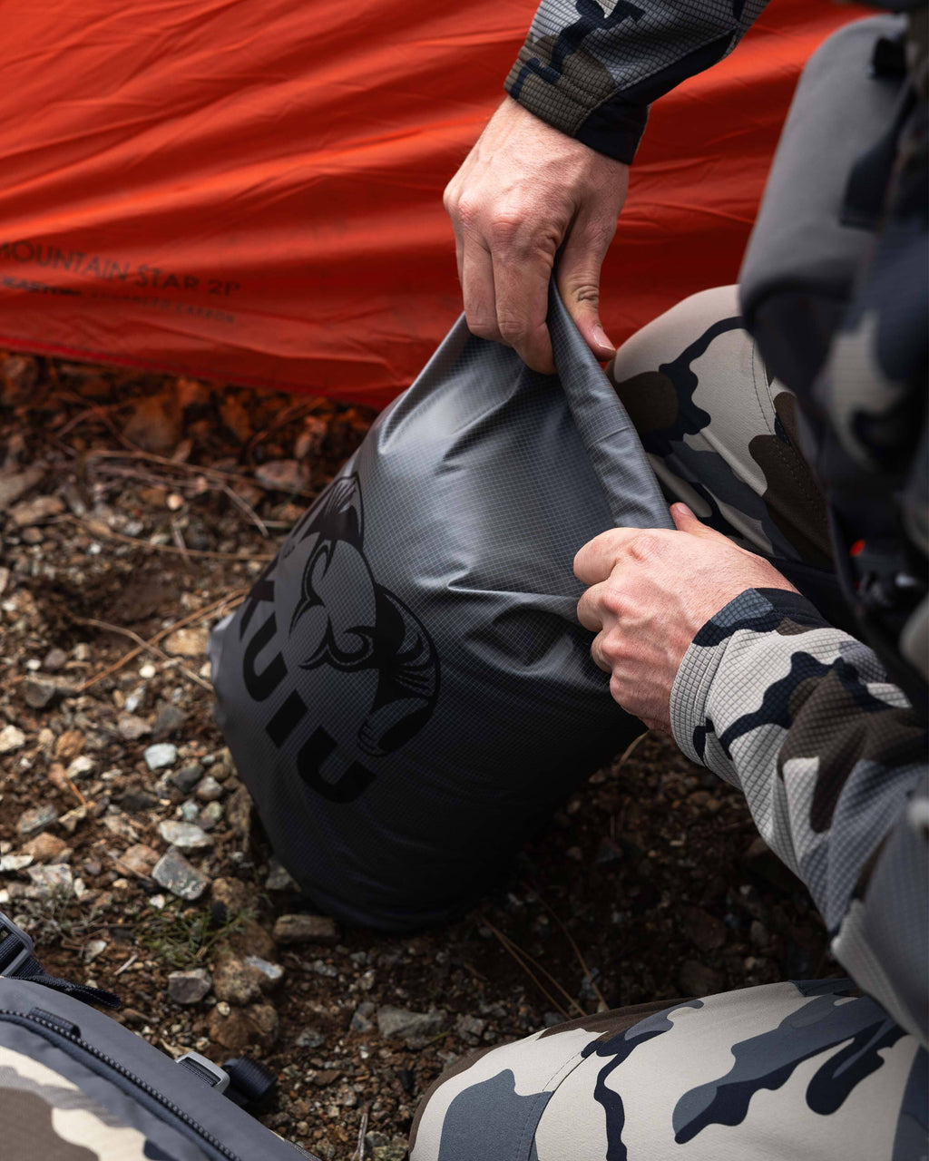 Hunter rolling the top of the Stone Grey HD Roll Top Dry Bag closed for waterproof seal
