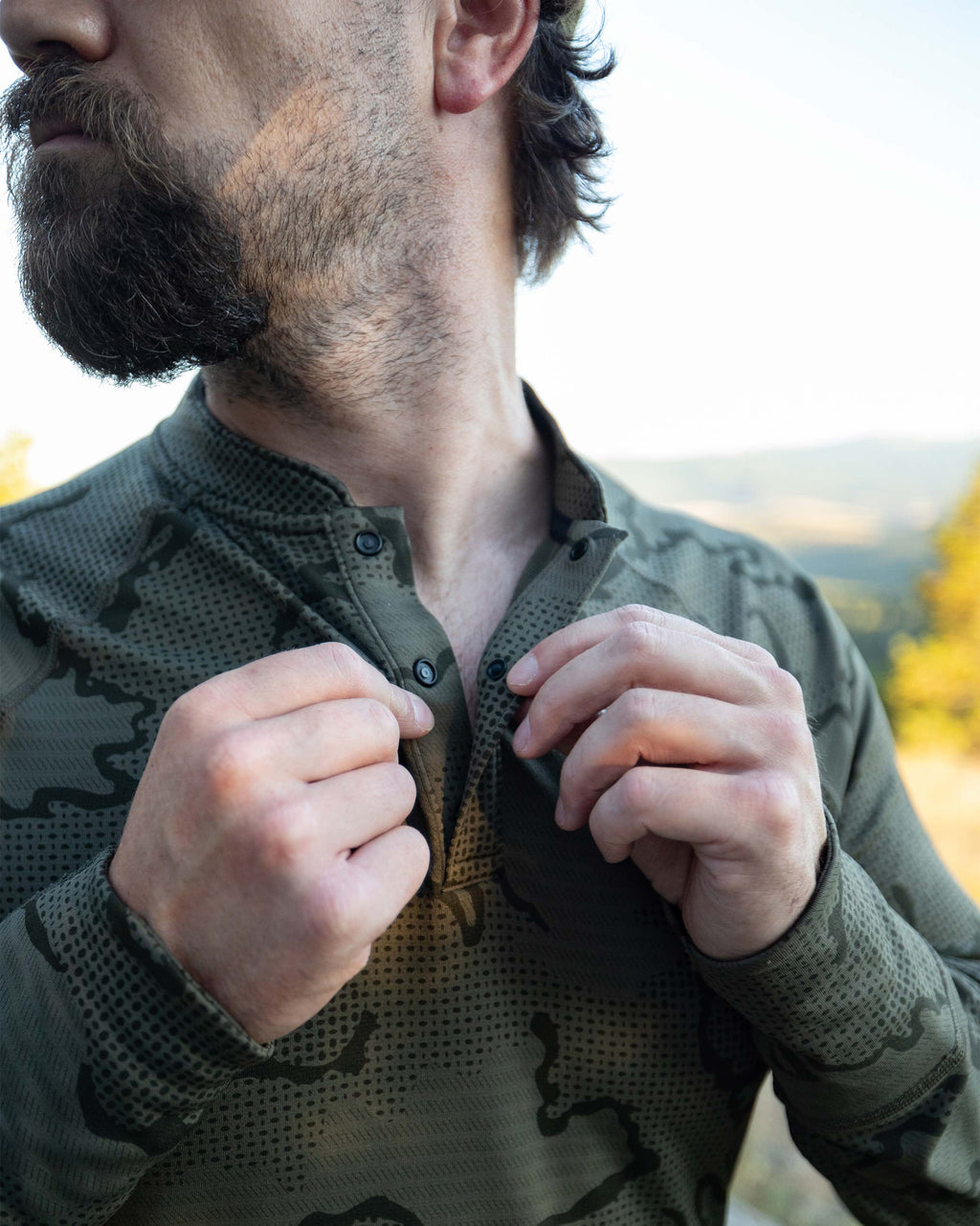Close-up view of Hunter snapping his shirt bottons on the Ridgepoint Fleece Henley Olive Green Tonal Pattern