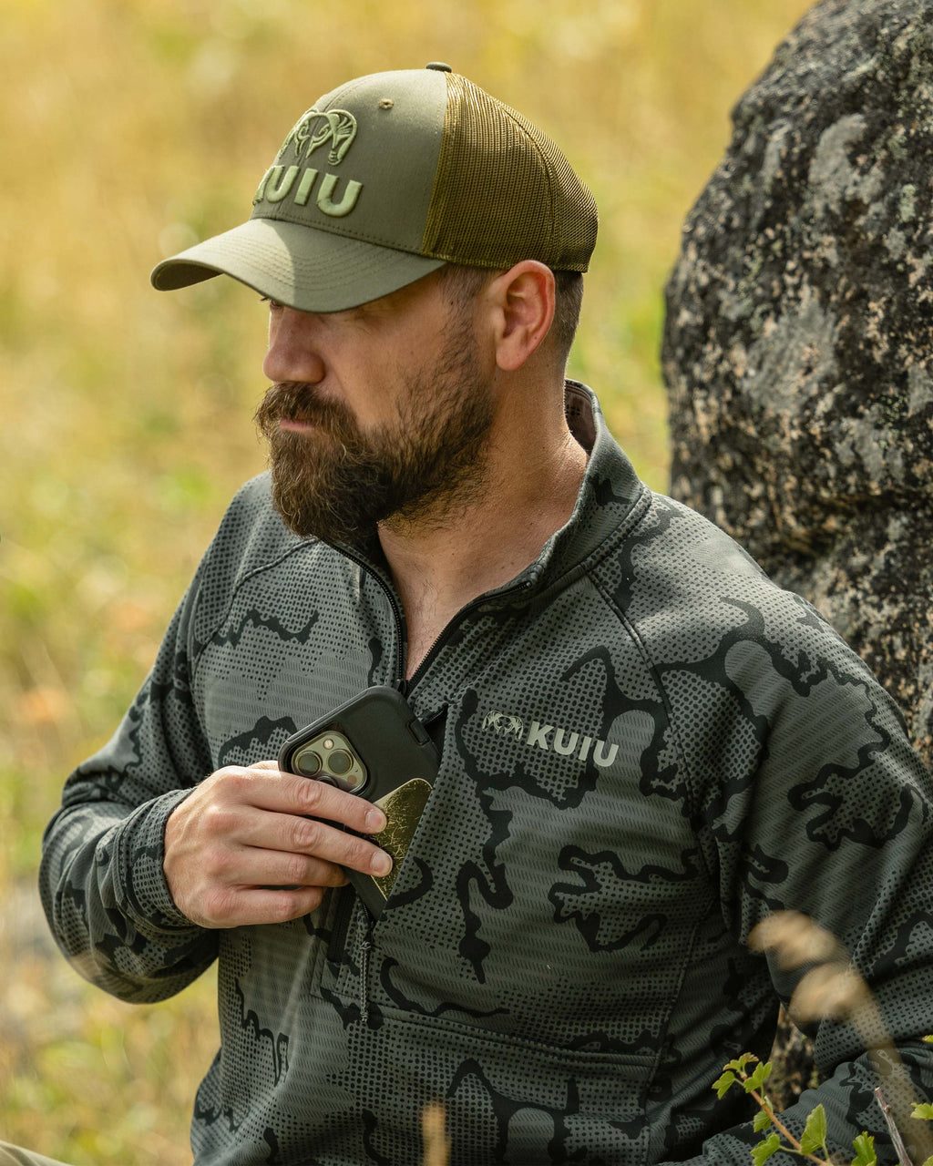 Hunter slipping a cellphone in his left chest pocket, wearing Ridgepoint Fleece Zip-T in Olive Green Tonal Pattern 