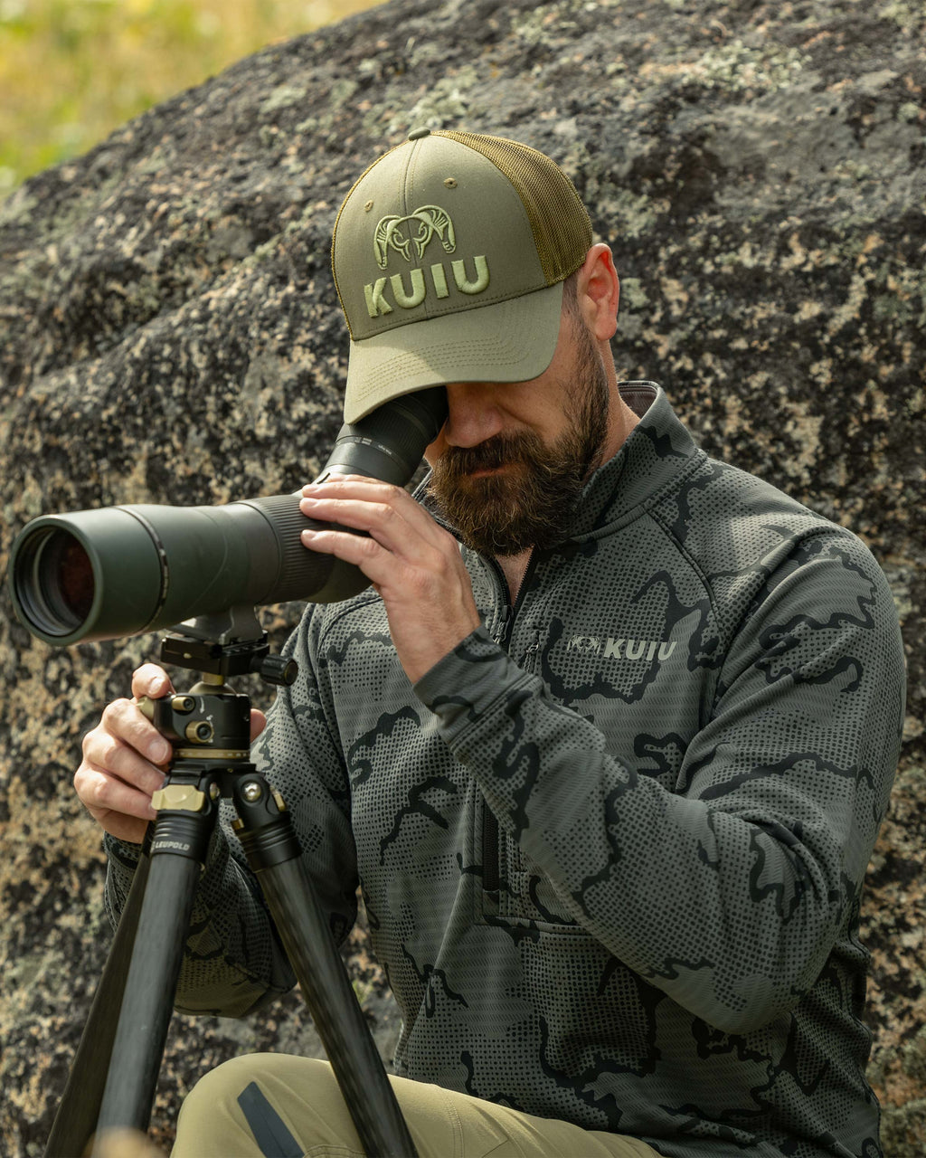 Hunter propped next to a rock, using his spotting scope, wearing Ridgepoint Fleece Zip-T in Olive Green Tonal Pattern 