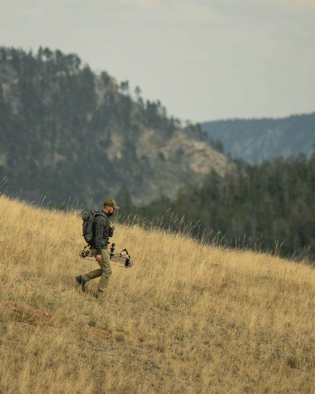Side view of Hunter hiking down the hill, wearing Ridgepoint Fleece Zip-T in Olive Green Tonal Pattern