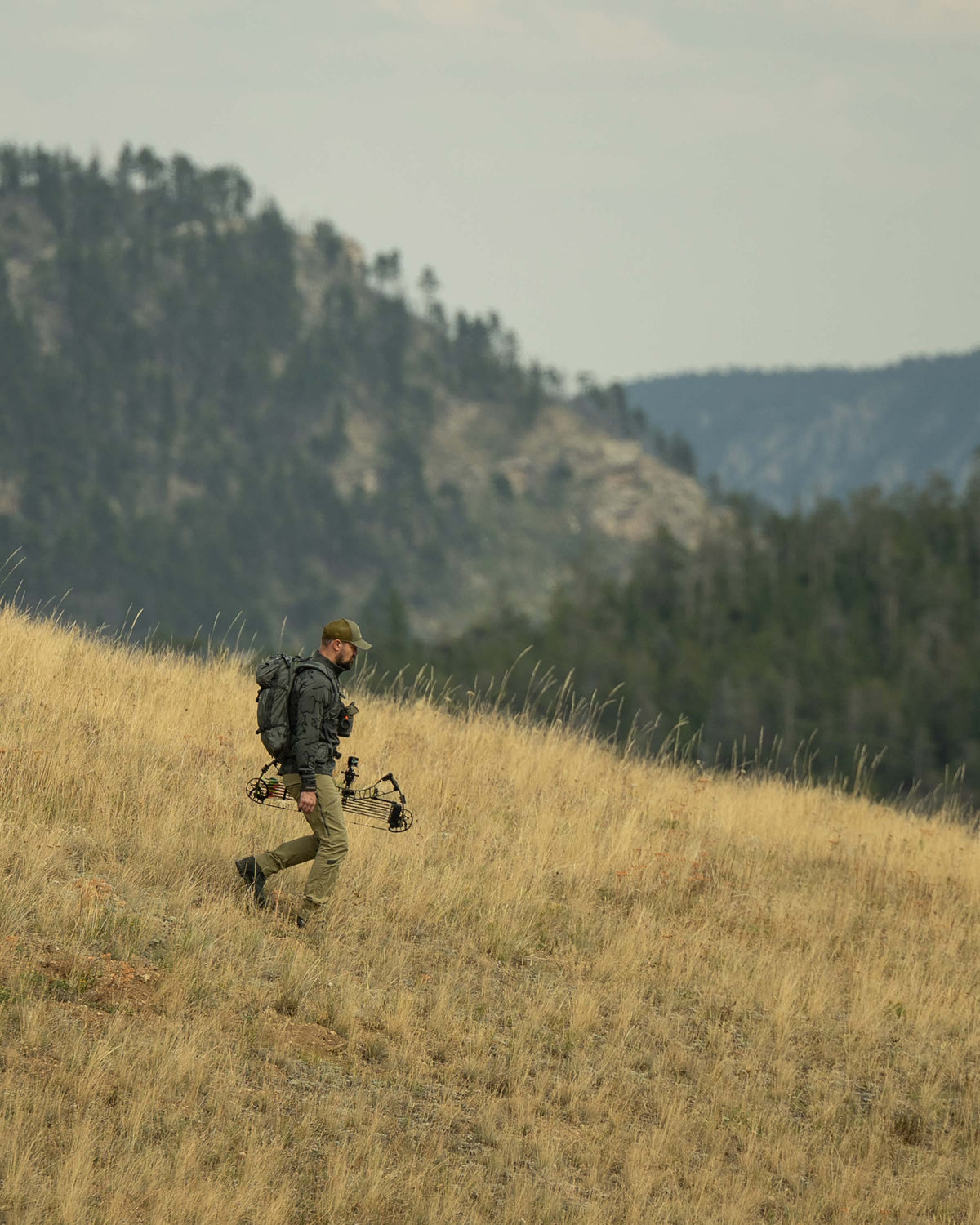 Side view of Hunter hiking down the hill, wearing Ridgepoint Fleece Zip-T in Olive Green Tonal Pattern