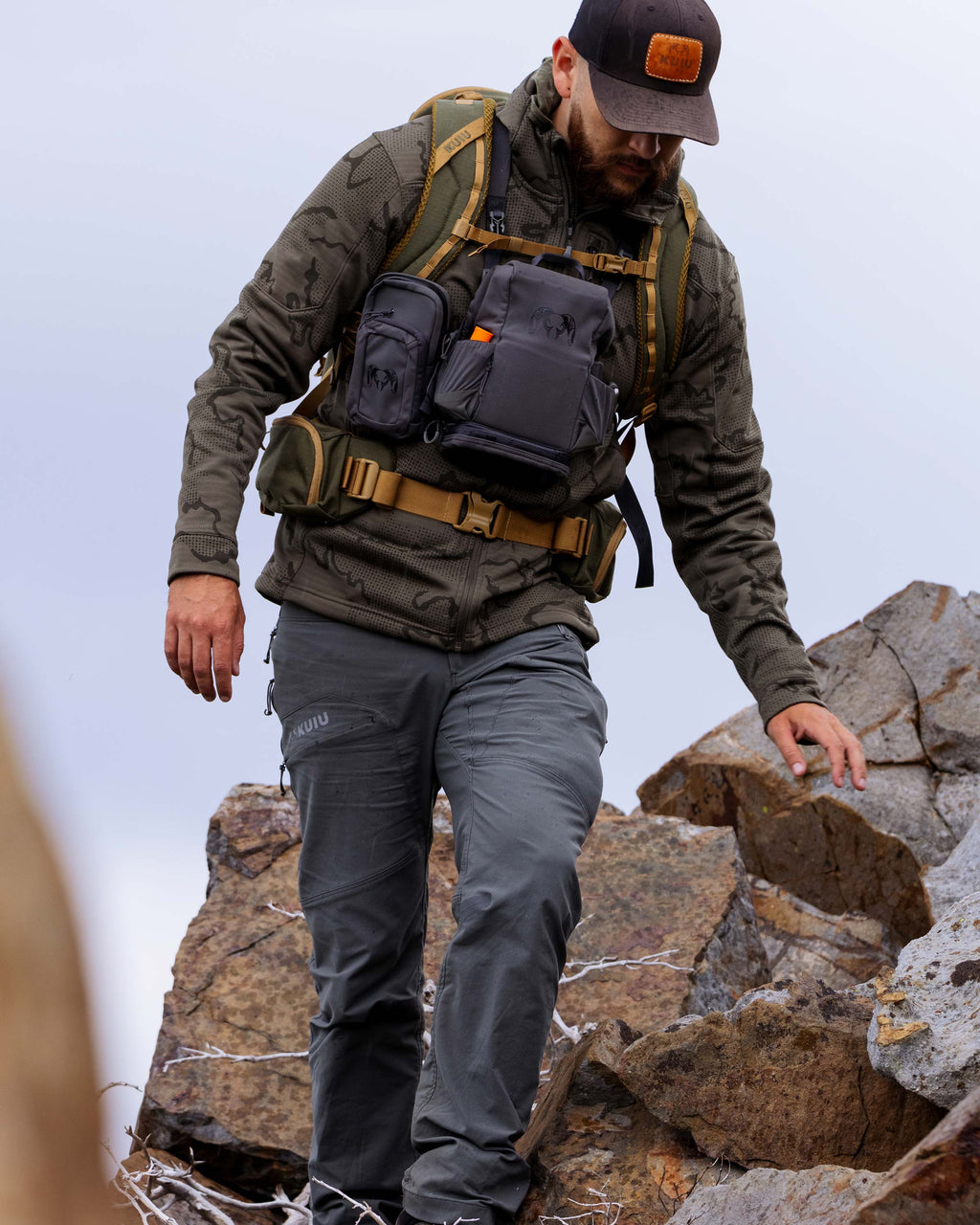 Hunter carefully hiking down rocky terrain, wearing Ridgepoint Fleece Hoodie in Ash Tonal Brown