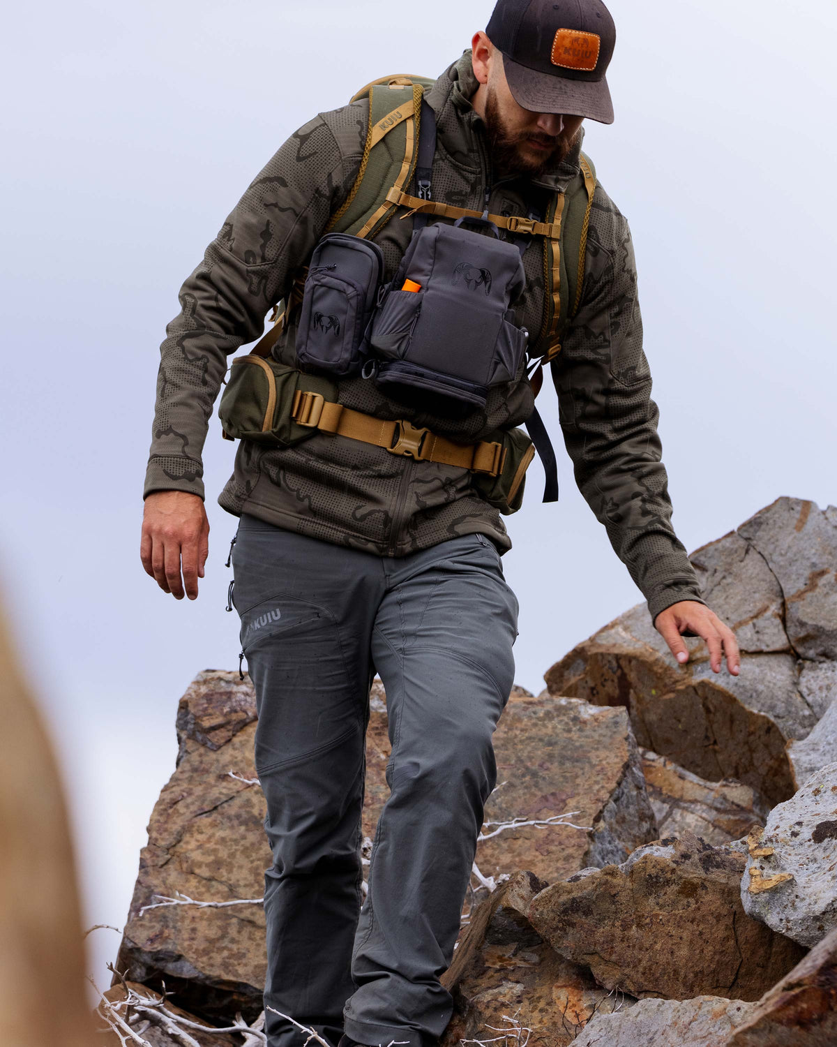 Hunter carefully hiking down rocky terrain, wearing Ridgepoint Fleece Hoodie in Ash Tonal Brown