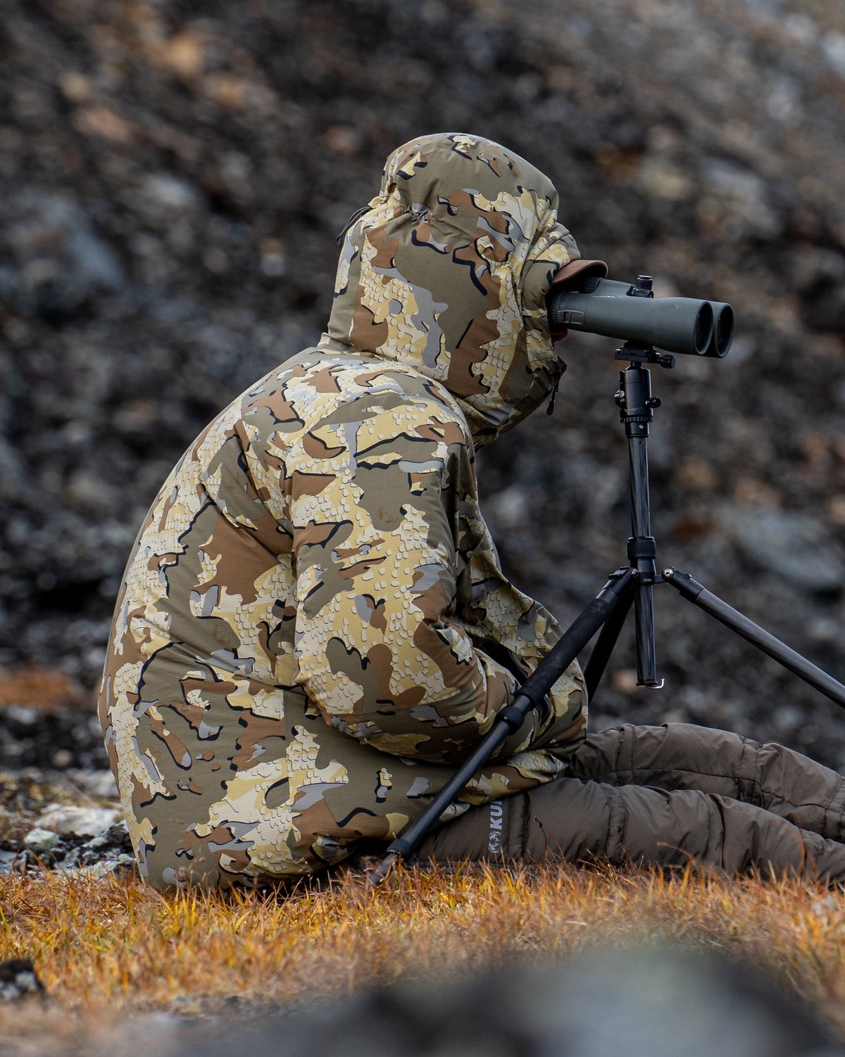 Side of hunter wearing Super Down Burner Parka in Valo Camouflage with hands in pockets
