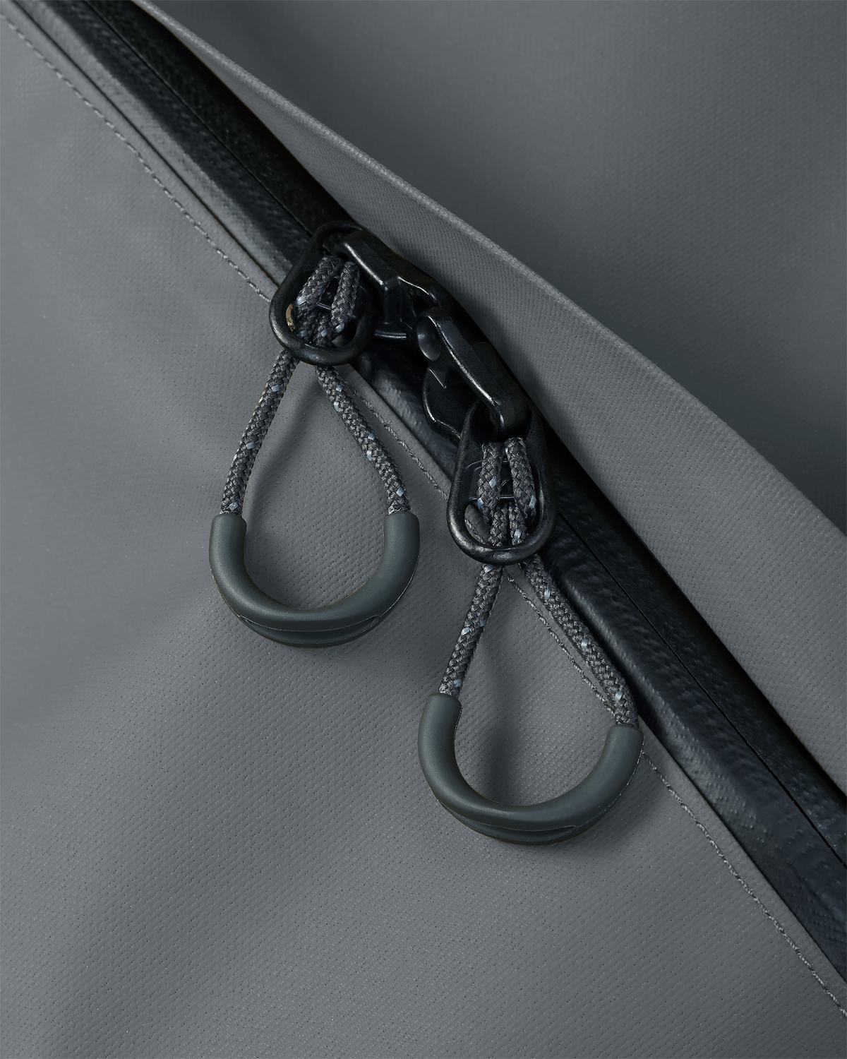 Macro view of corded pull tabs attached to the zipper slider on the Taku BLSTX 4200 Duffel in Gunmetal Grey