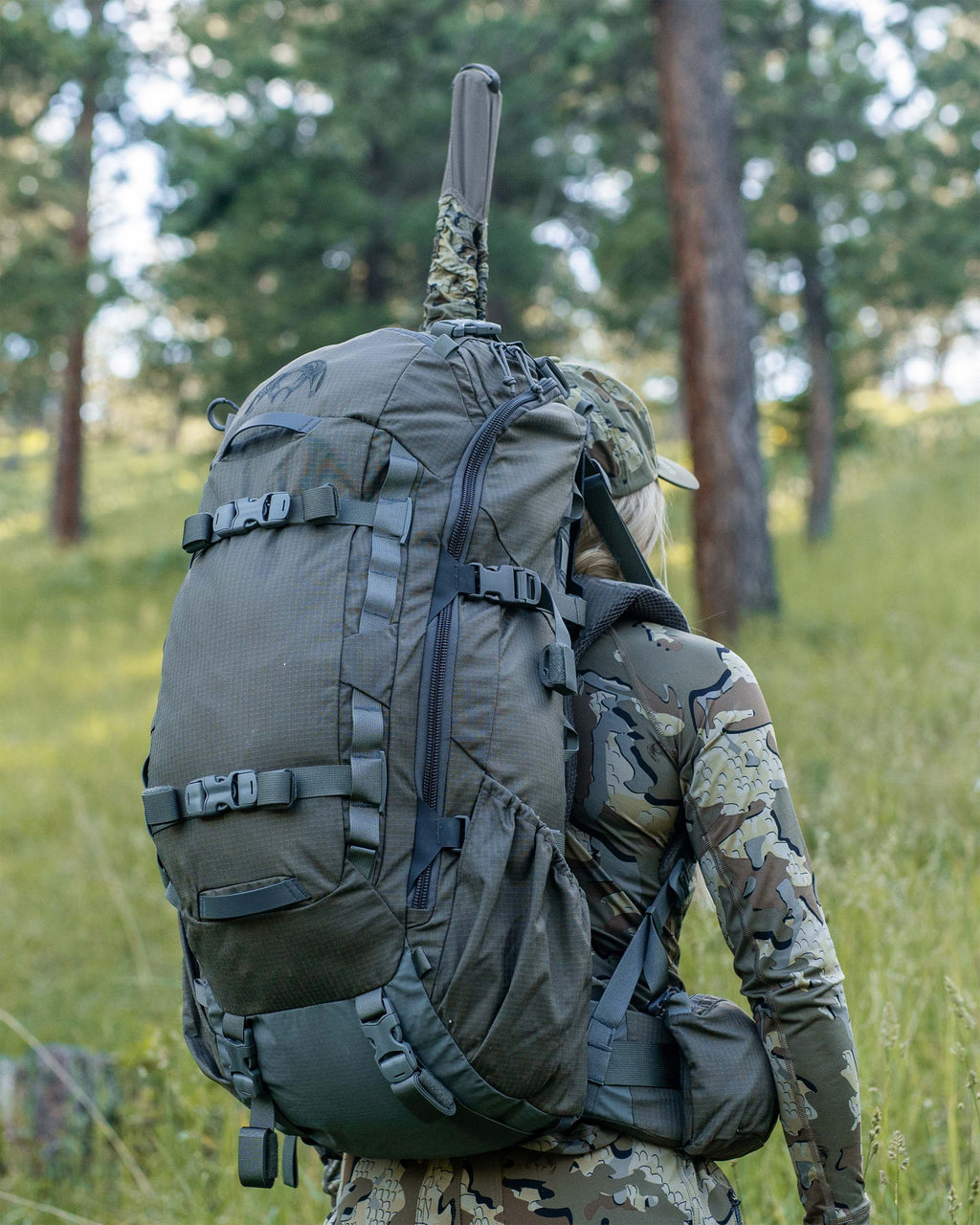 Women hiking through a grassy forest with an ICON 6 3500 Pack in Ash Brown