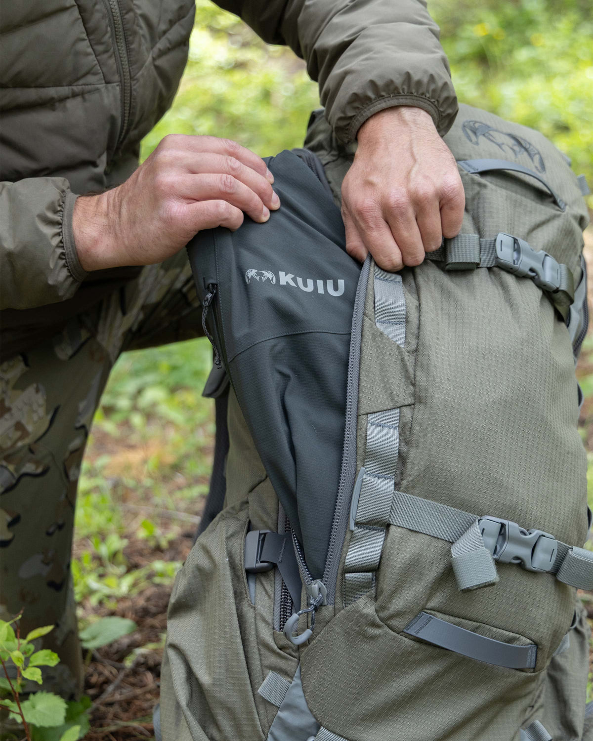 Hunter showing outer pocket with side access on KUIU ICON 6 Pack in Ash Brown.