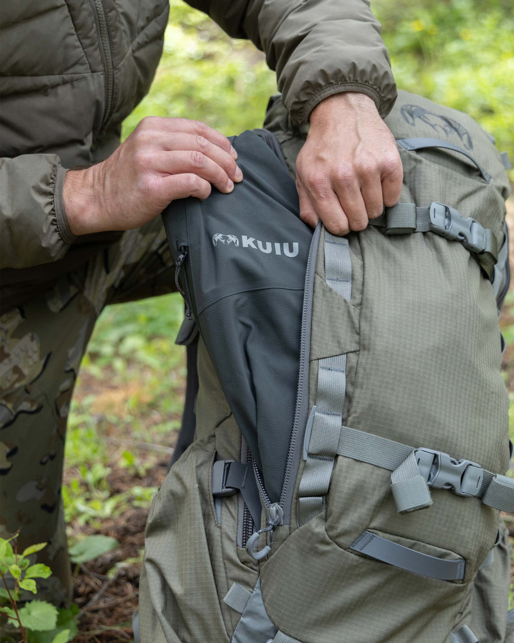 Hunter showing outer pocket with side access on KUIU ICON 6 Pack in Ash Brown.