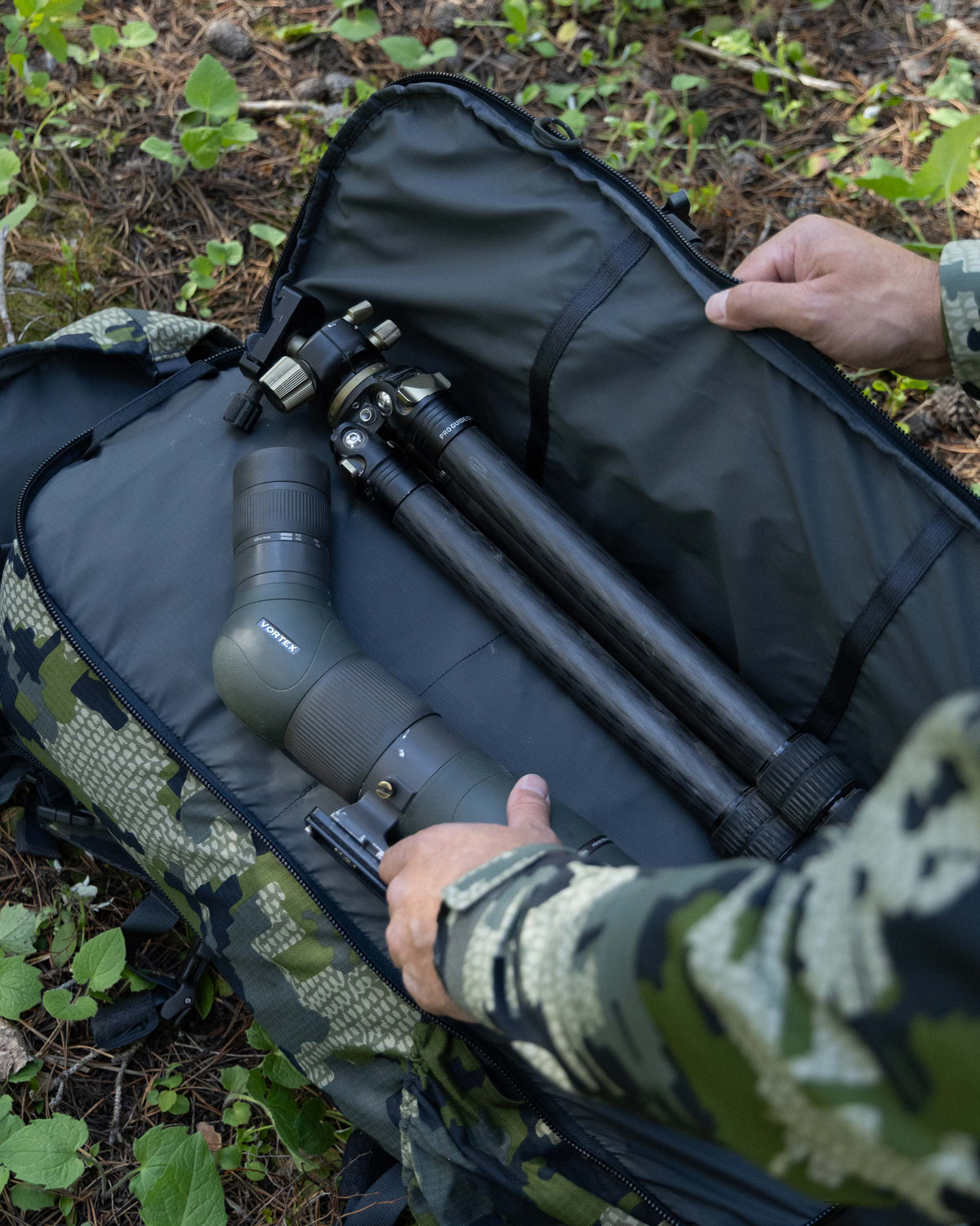 Hunter showing divide storage pocket for optics storage on KUIU ICON 6 4500 hunting pack in Verde Camouflage.