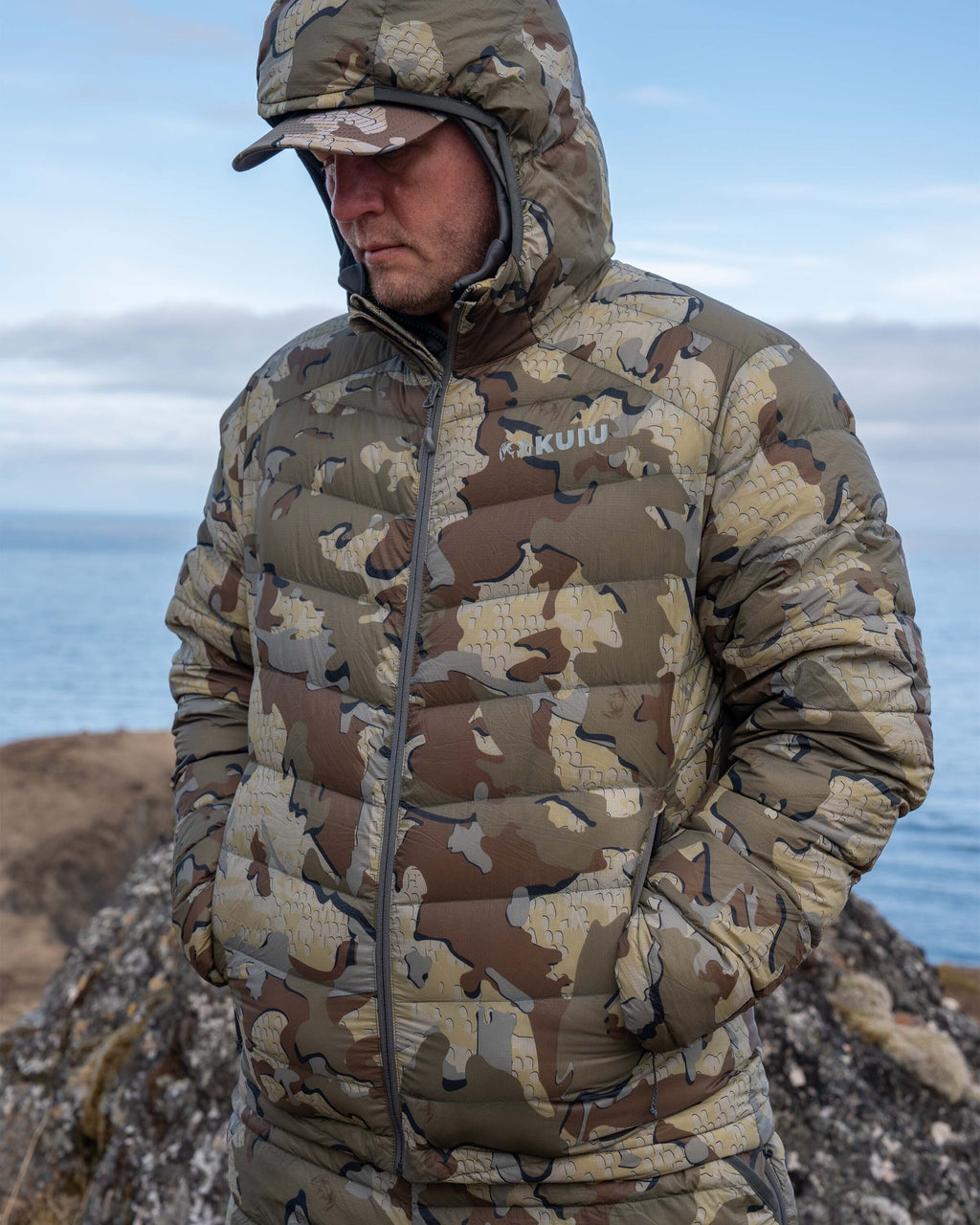 Hunter with hands in pocket wearing Super Down LT Hooded Jacket in Valo Camouflage