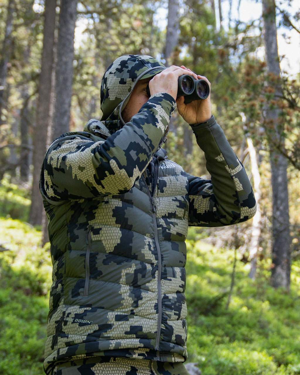 Hunter Glassing in Green Wooded Area with Super Down LT Vest in Verde Camouflage