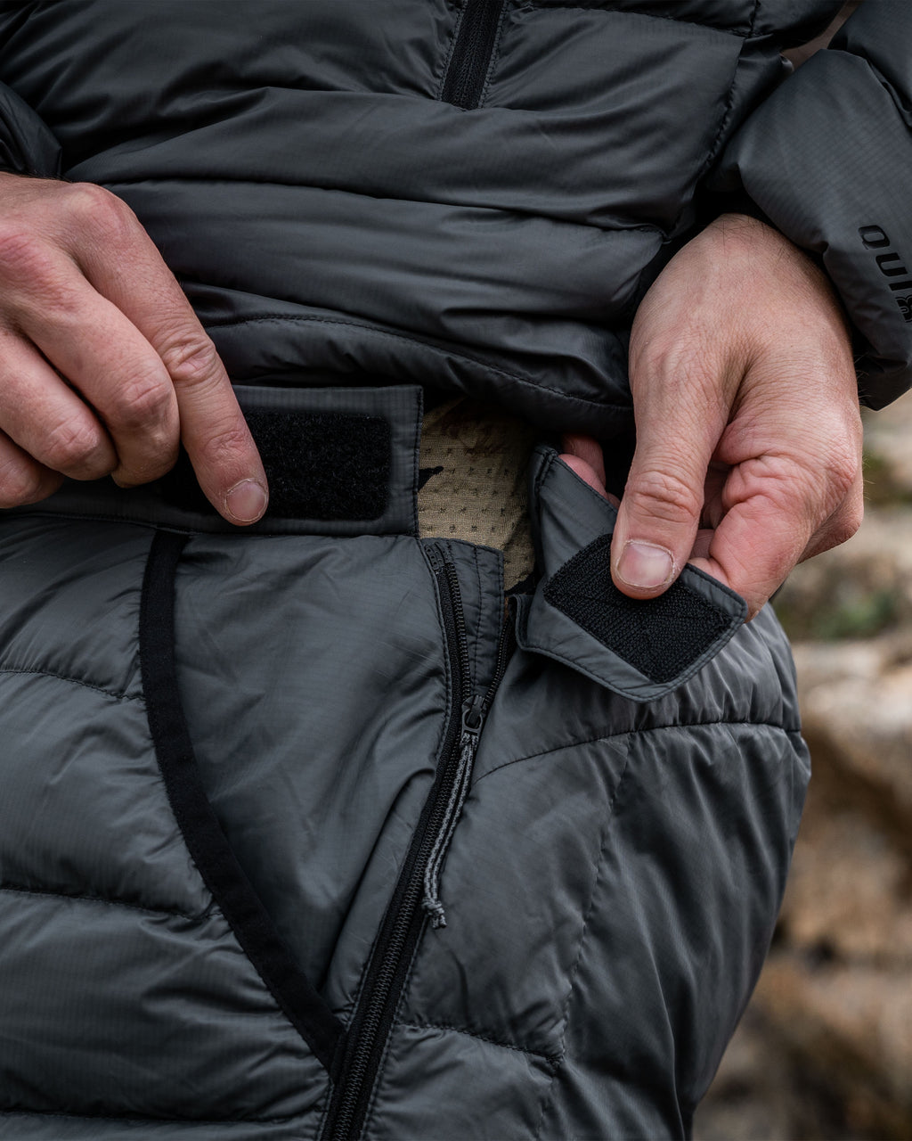 Side of Super Down LT Pants in Gunmetal Grey Highlighting Open Hand Pocket with Stretch Bound Edge, Full Zip Sides with hook & loop tabs at waist