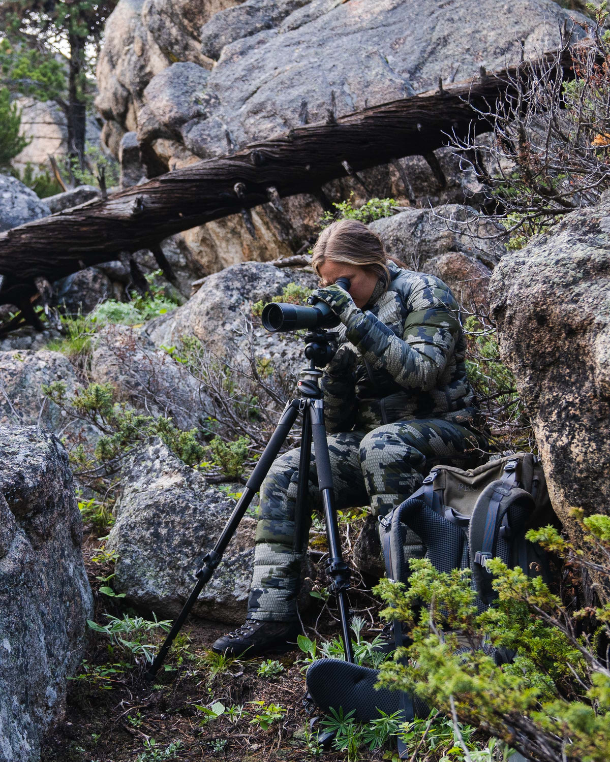 Hunter Watching Game Through Spotting Scope Wearing Women's Super Down LT Jacket and Pants in Verde Camouflage