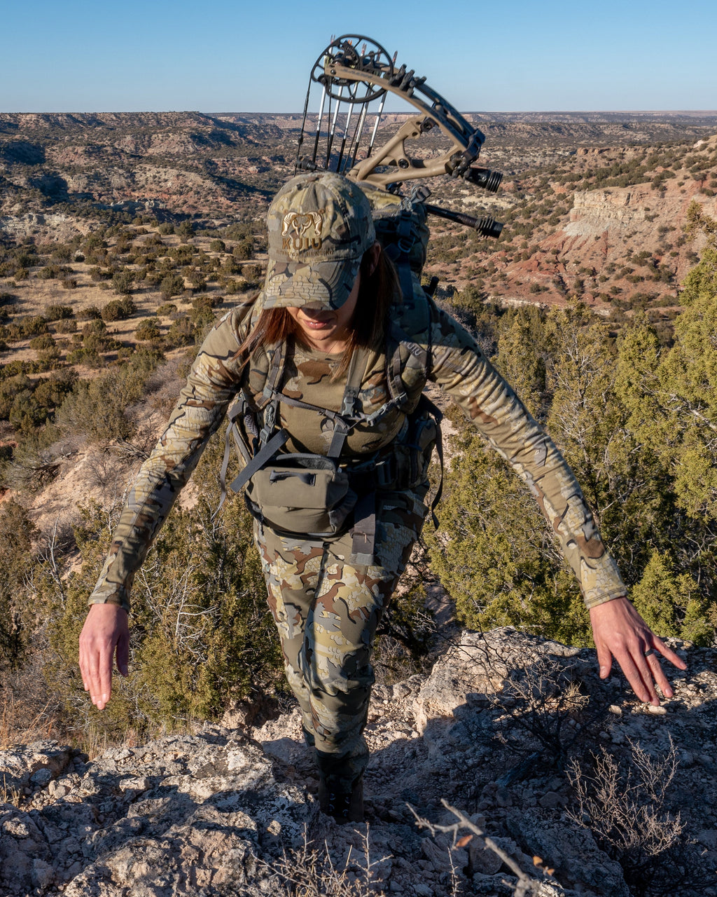 Female hunter climbing rock face wearing Women's ULTRA Merino 145 LS Crew in Valo Camouflage