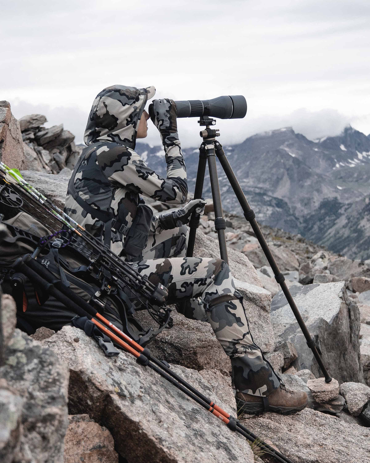 Female hunter sitting on rocks, glassing, wearing Women's Attack Pant in Vias Camouflage