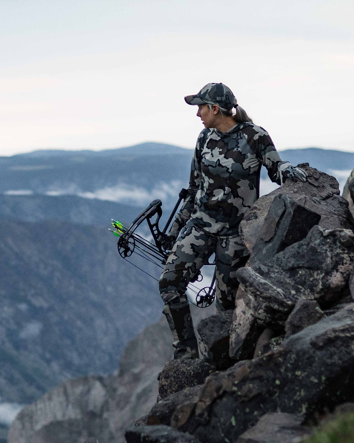 Female hunter resting on rocks scouting area wearing Women's Attack Pant in Vias Camouflage