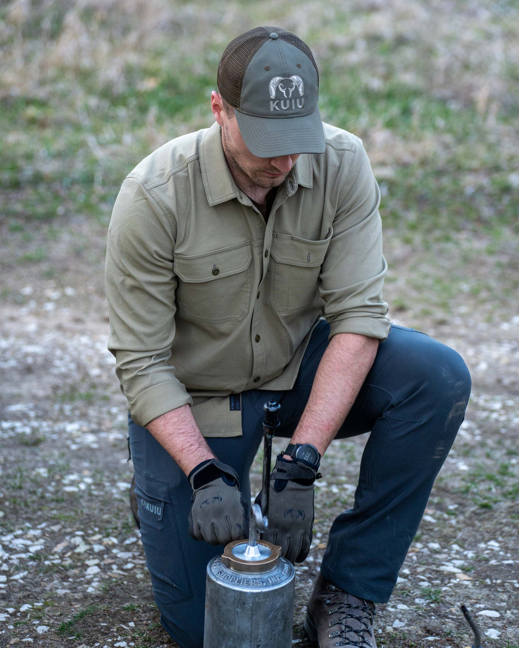 Hunter kneeling to prep drip torch, wearing Motive LS Work Shirt in Khaki