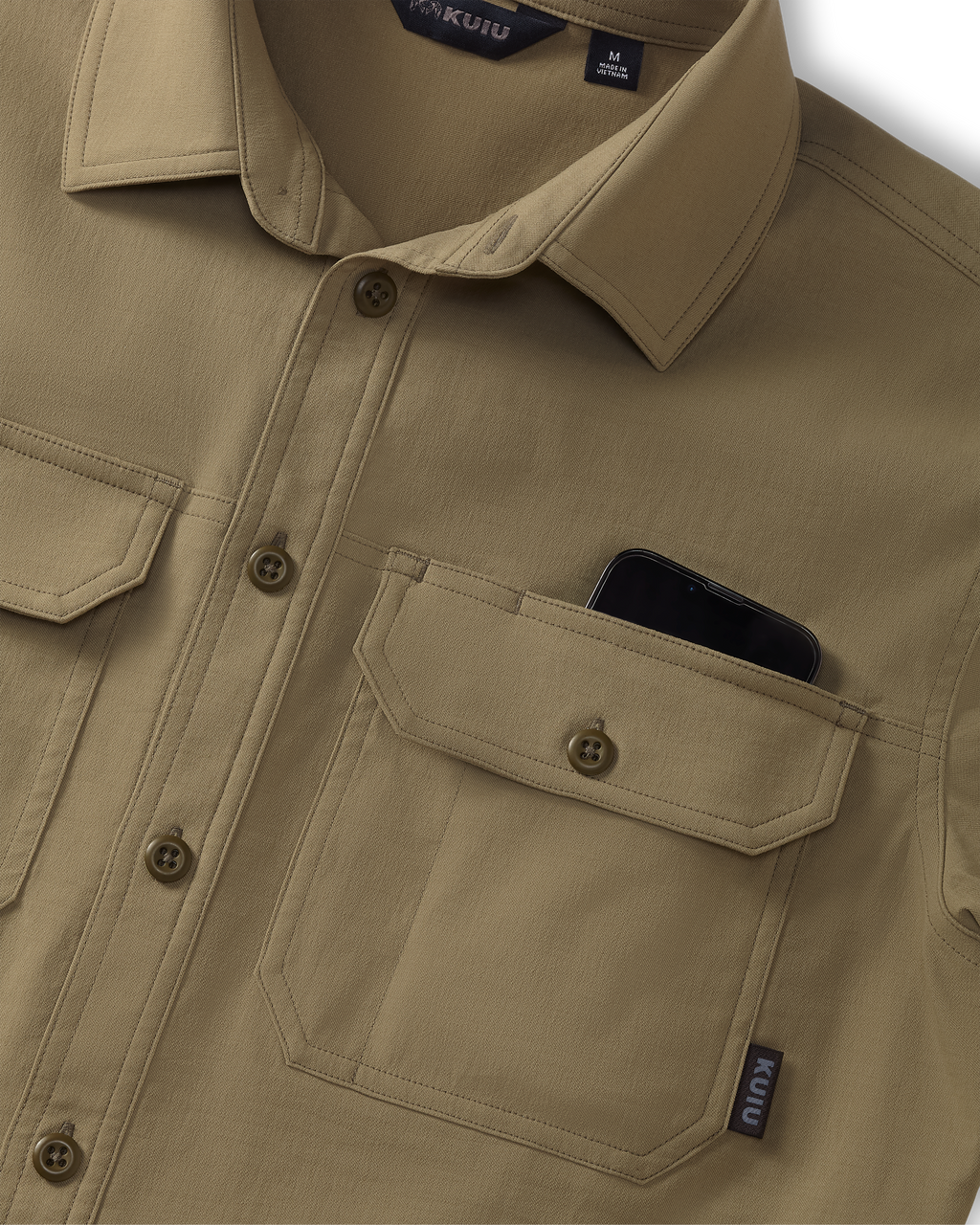 Close-up of Motive Short Sleeve Workgrade Button‑up Shirt in Khaki showing the collar, button placket, and dual chest pockets, with a smartphone partially visible inside one pocket.
