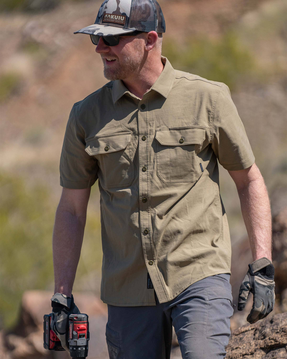 Model holding a cordless screwdriver, wearing Motive Short Sleeve Work Shirt in Khaki