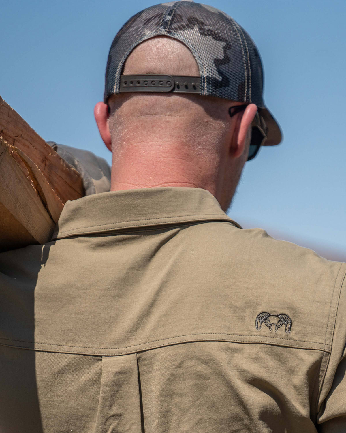 Back shot of model captured KUIU logo on the right side shoulder of Motive Short Sleeve Work Shirt in Khaki