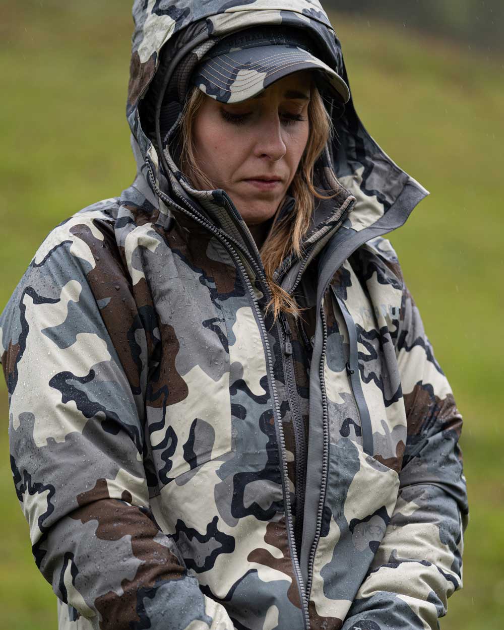 Front of Hunter Standing in the Rain Zipping Up Women's Chugach TR Rain Jacket in Vias Camouflage