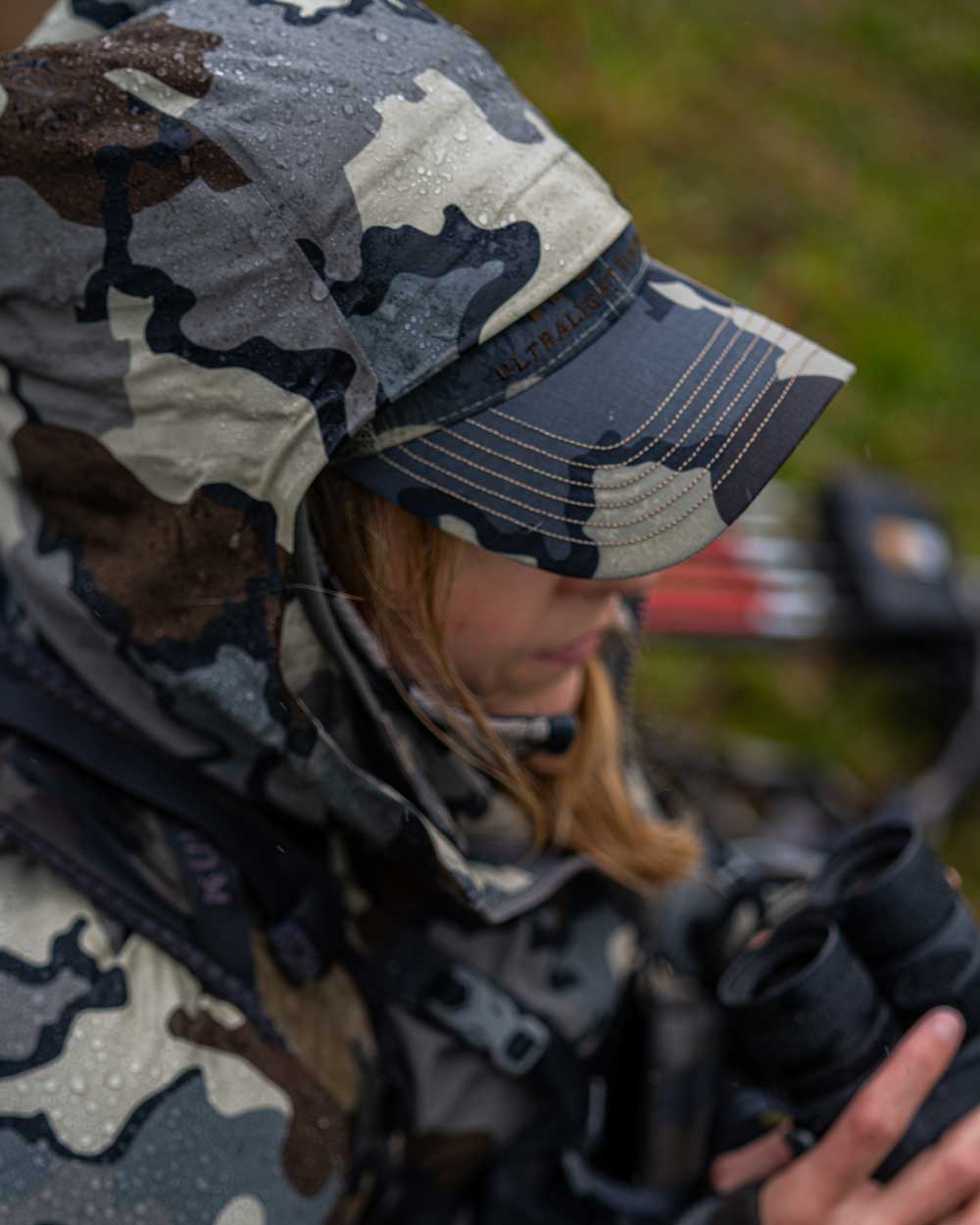 Top view of female hunter in rainy conditions using hood with hat underneath wearing Women's Chugach TR Rain Jacket in Vias Camouflage
