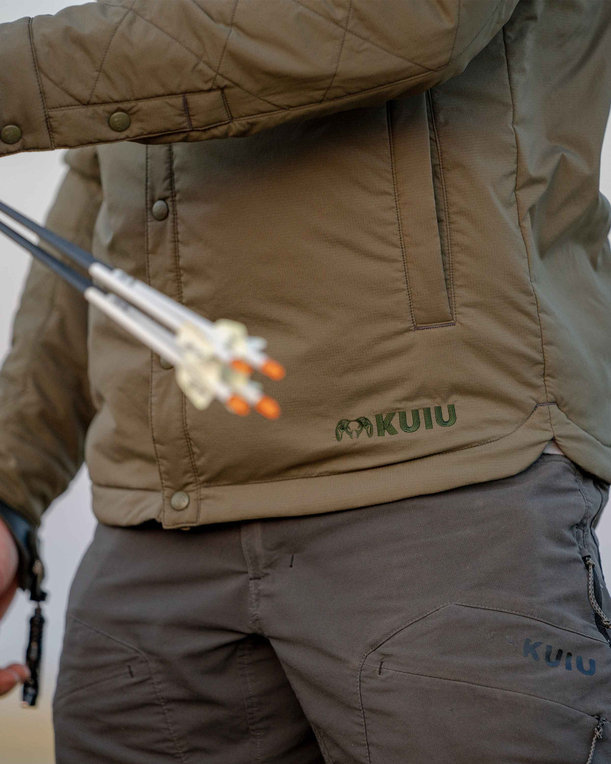 Bottom half front view of Base Camp Insualted Snap shirt showing hand pockets, cuff and front snaps in Ash Brown