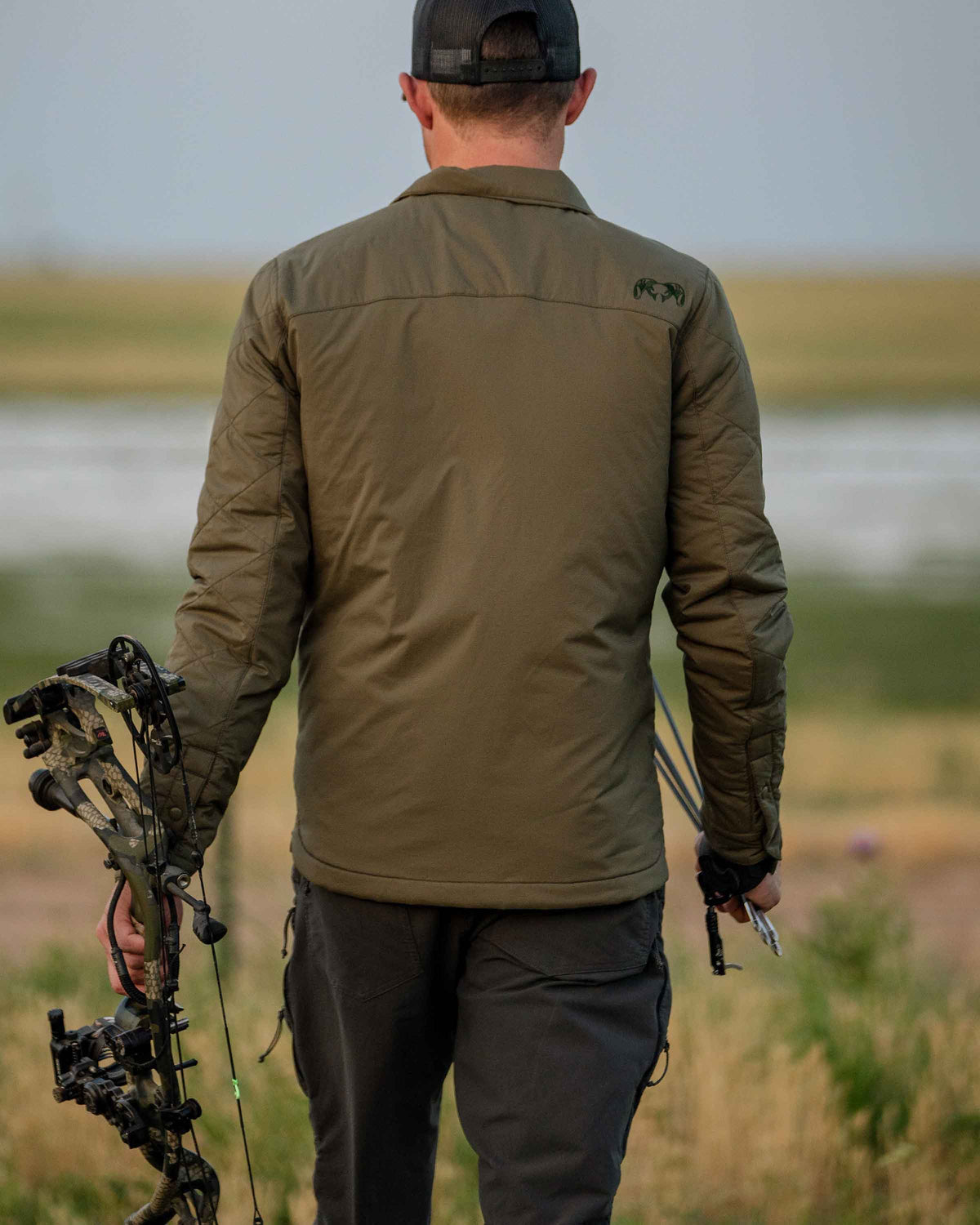 Back of Base Camp Insulated Snap Shirt in Ash Brown with hunter holding bow in an open field