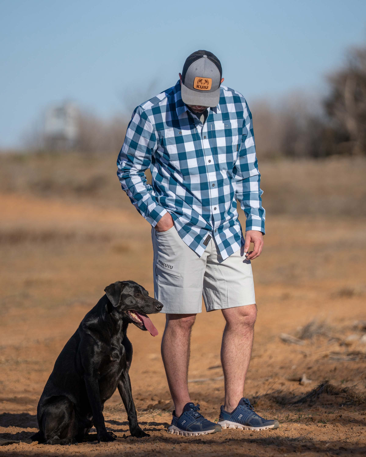 Hunter wearing Switchback Short in Lunar Grey, looking down at the black labrador sitting next to him