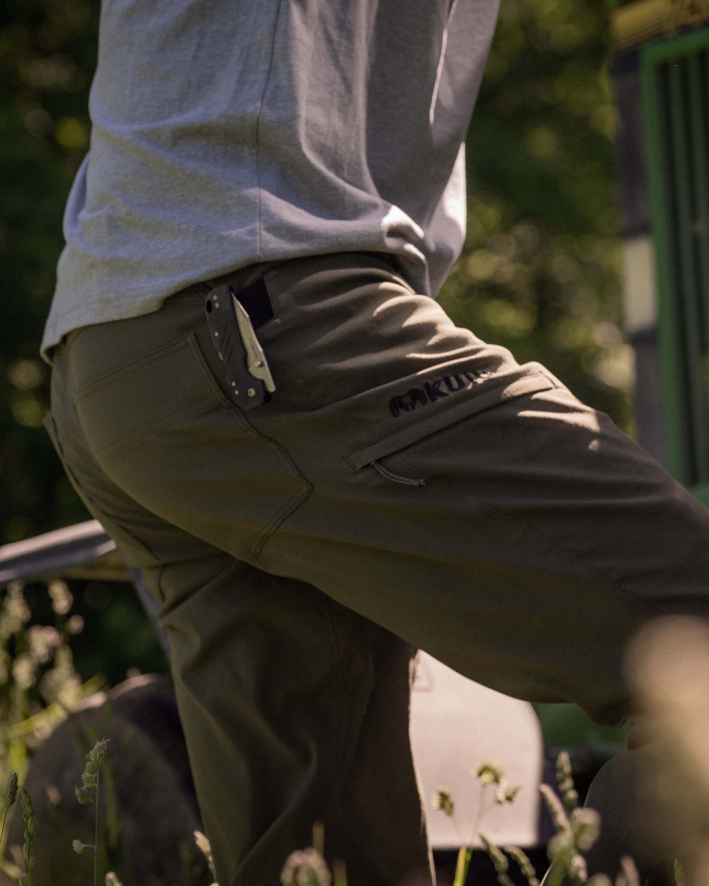 Side of Hunter Wearing Switchback Pants in Olive Green Color Highlighting Reinforced Right Hand Knife Feature