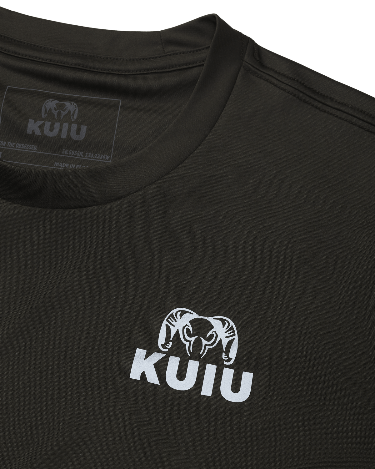 Close-up of the front neck area of the Velocity LS Crew in Black, featuring reflective KUIU chest logo