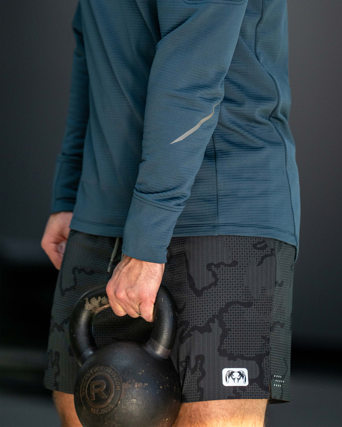 Close-up of a man holding a black kettlebell by their side wearing EnduroTrainer Lined 7" Short in Dark Iron Tonal