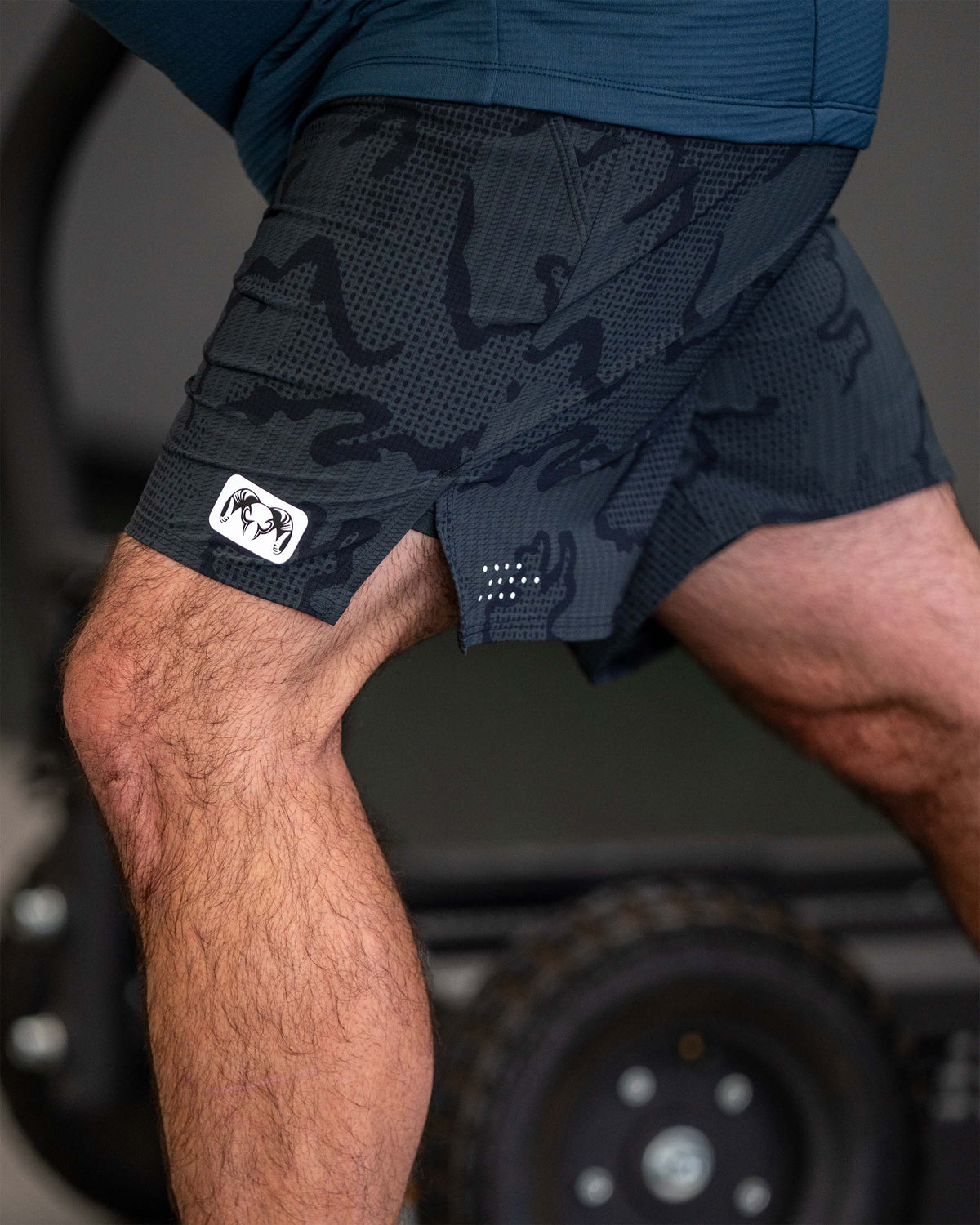 Close-up of KUIU Ram reflective patch on bottom left leg hem of EnduroTrainer Lined 7" Short in Dark Iron Tonal Grey
