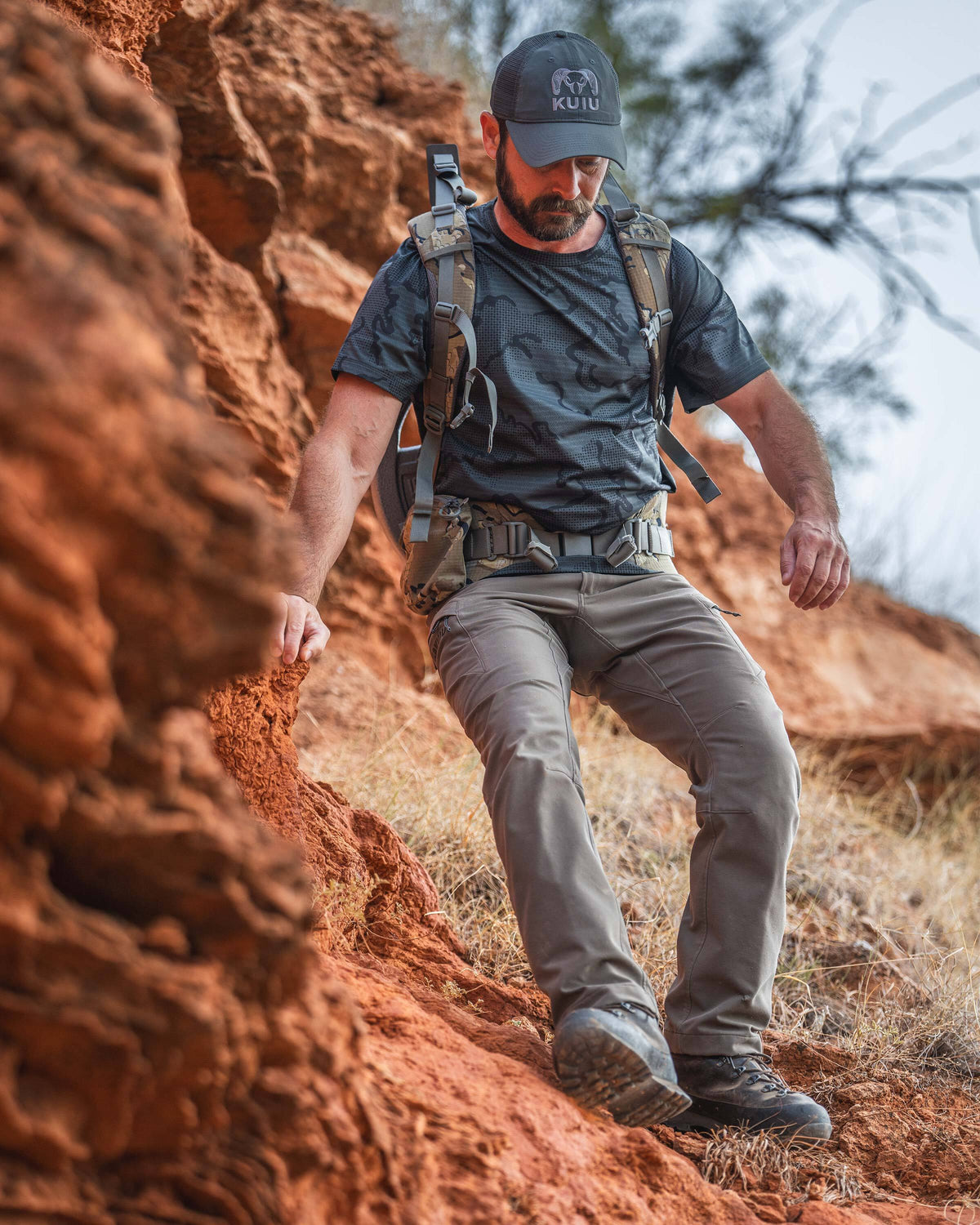 A man hiking down a steep red rock slope wearing a TrailTrainer Short Sleeve Crew in Dark Iron Tonal.