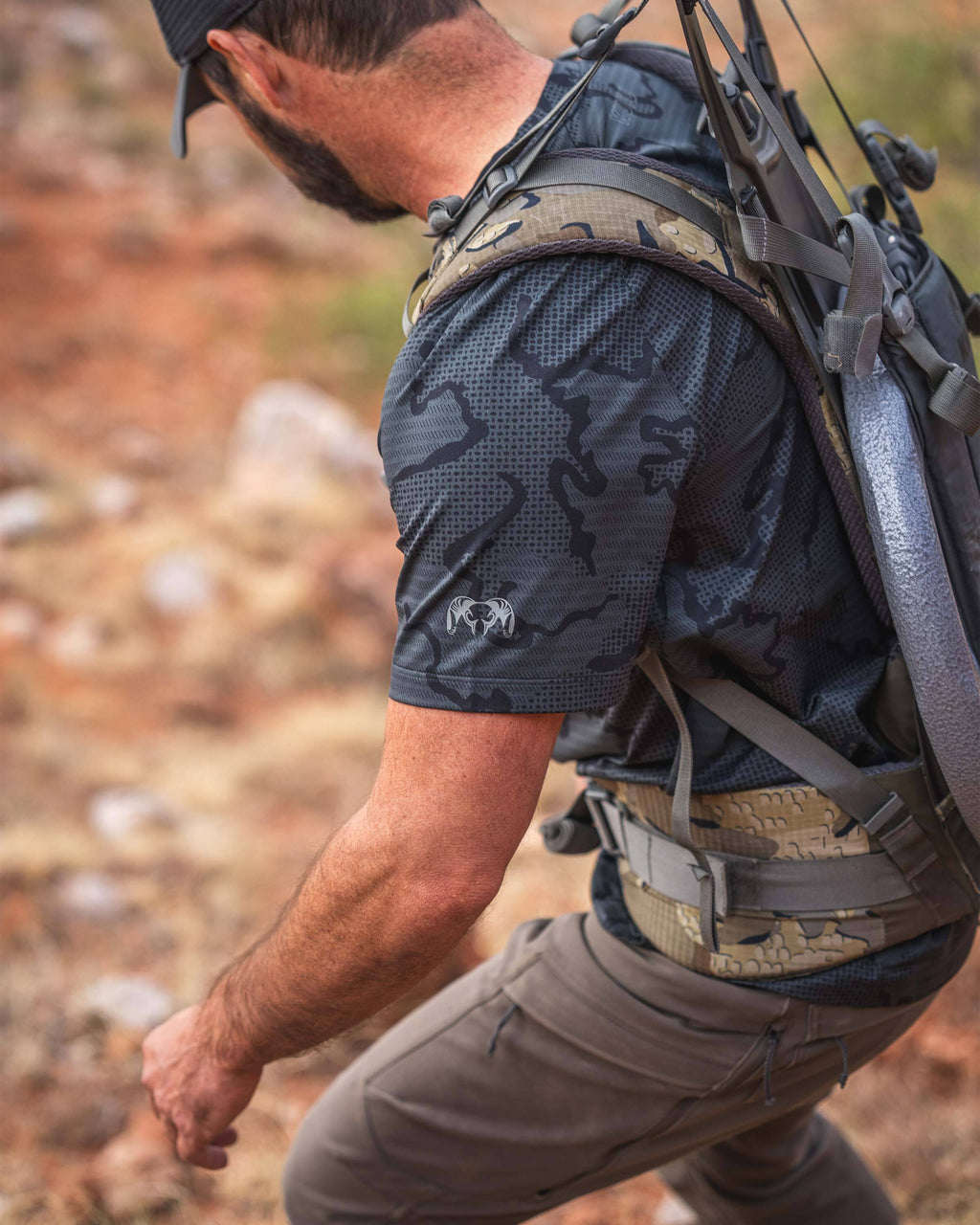 A man carefully hiking down a steep and rocky hill wearing a TrailTrainer Short Sleeve Crew in Dark Iron Tonal.