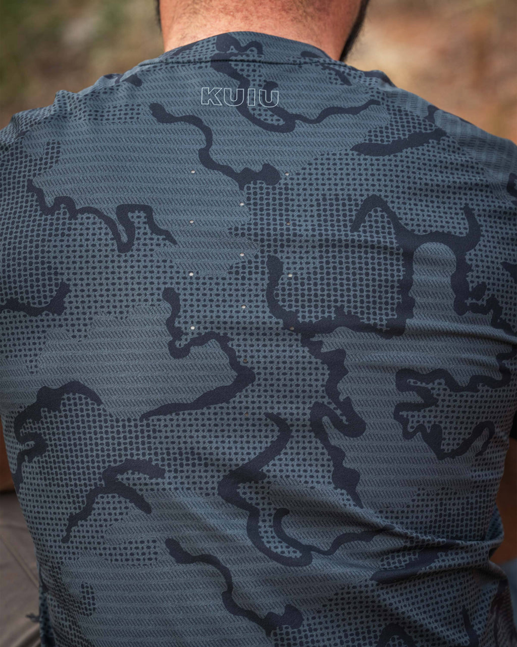 Close-up, back view of a man wearing TrailTrainer Short Sleeve Crew in Dark Iron Tonal, showing laser-perforated venting between shoulder blades.