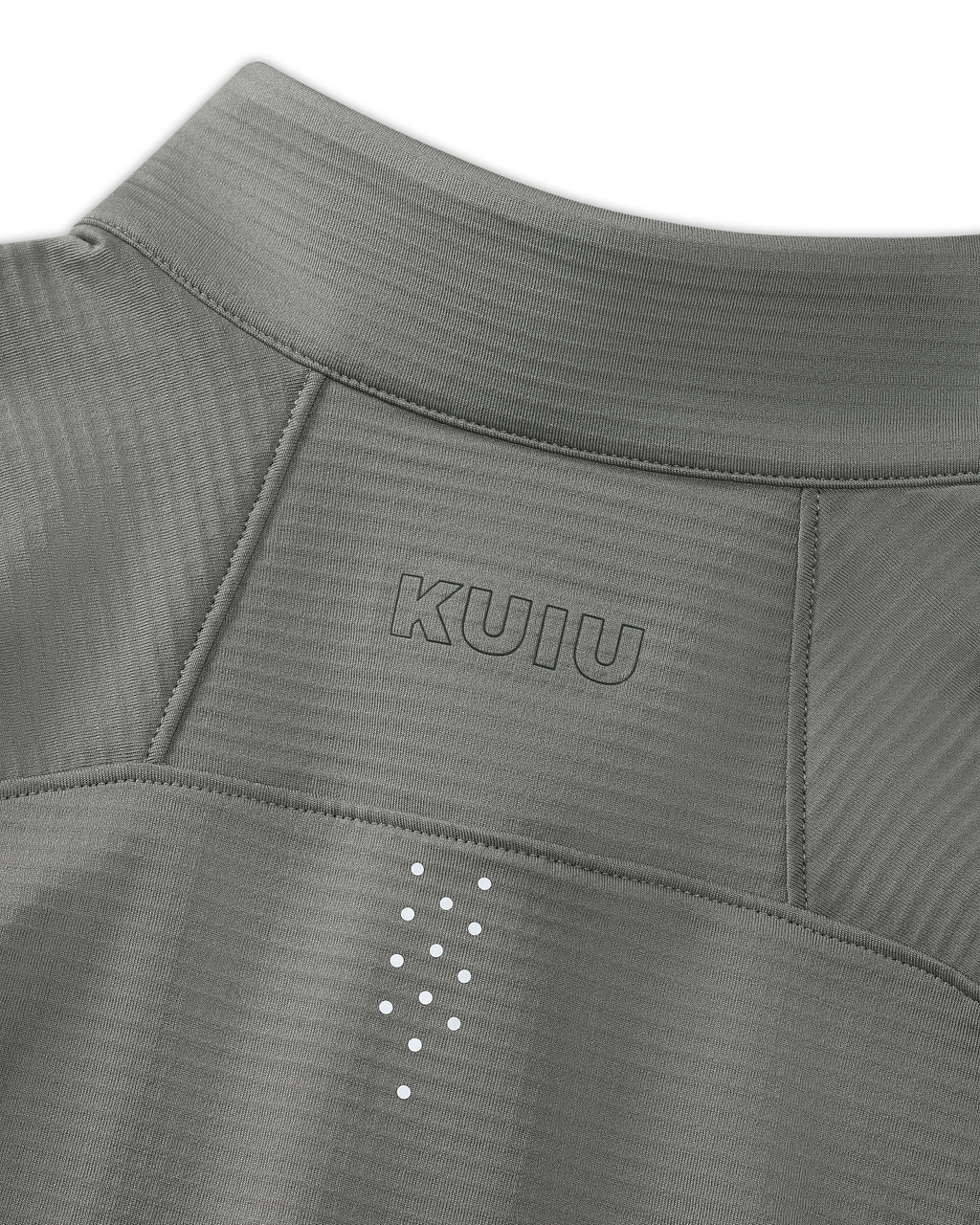 Close-up of upper back KUIU Euduro Trainer Zip-T in Shadow Grey, showing fabric subtle horizontal texture, KUIU logo printed above small reflective dots arranged vertically between the shoulder blades