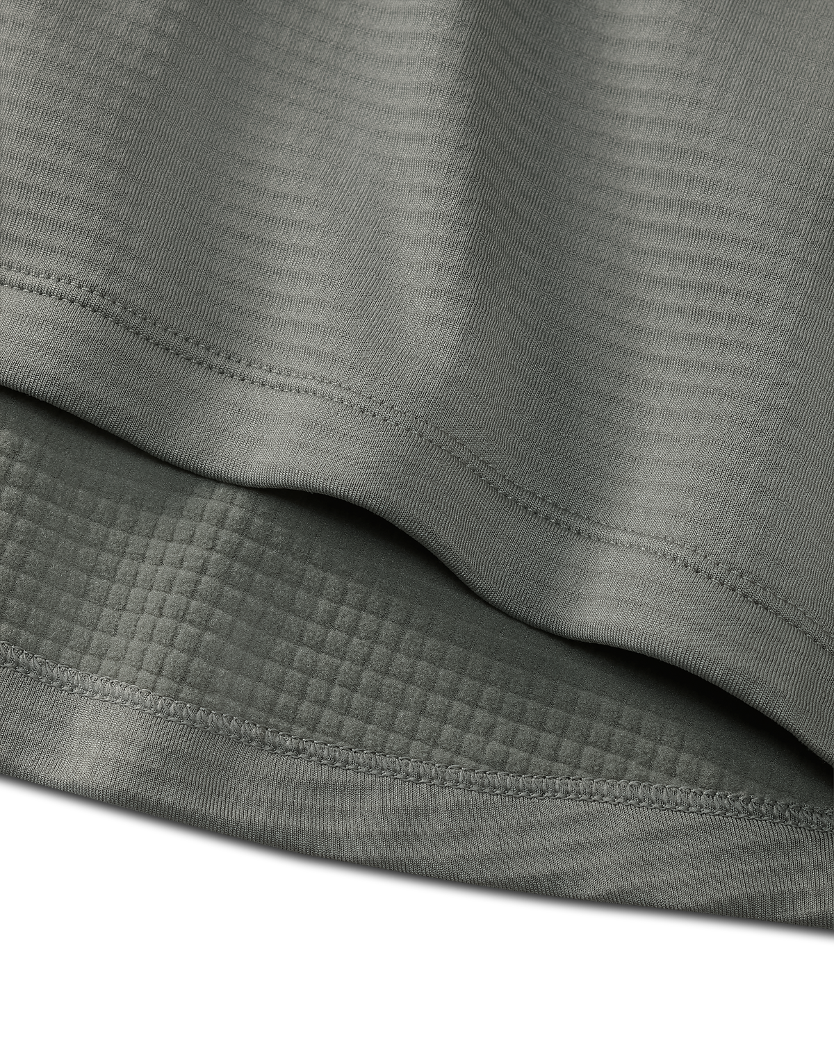 Close-up detail of bottom hem stitching on the EnduroTrainer Zip-T in Shadow Grey